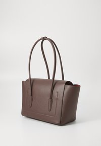 Borsa tote in pelle marrone con finitura testurizzata, forma rettangolare, due manici lunghi e apertura superiore che rivela un interno rosso a contrasto.