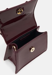 Burghundy patent leather handbag, rectangular shape, features a gold snap closure, and a black interior. Clean lines with accent stitching.