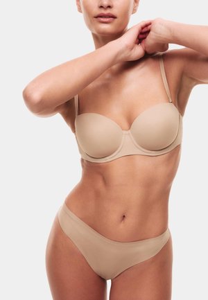 Beige beha met gevormde cups en dunne bandjes, gecombineerd met bijpassende hoge taille slipjes. Gladde textuur met een naadloos design.