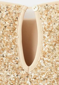 Tessuto di paillettes dorate al collo con un'apertura rotonda e chiusura a bottone, con fodera morbida beige e texture liscia.