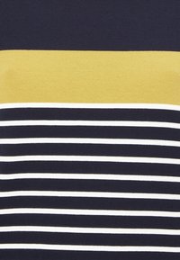 Bavlněné tričko má horizontální pruhy v námořnické modré a bílé barvě, s pevným žlutým pruhem na vrchu. Hladká textura, ležérní design.