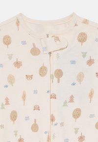 Combinaison légère beige avec un motif inspiré de la nature comportant des arbres, des ours et des feuilles dans des couleurs douces. Fermeture à bouton au cou. Tissu doux.