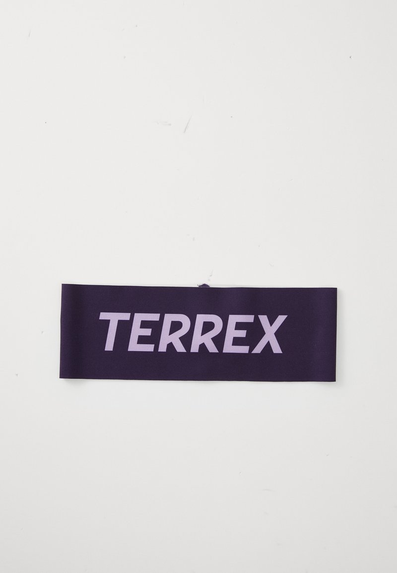 Ljubičasta tkanina oznaka s natpisom "TERREX" u podebljanim, svijetlosmešim slovima. Glatka tekstura, pravokutni oblik, minimalistički dizajn.