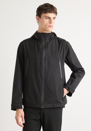 Veste légère noire avec une capuche, dotée d'une fermeture éclair intégrale, de deux poches poitrine zippées et d'une texture lisse, conçue pour les activités en plein air.