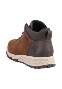 Botte de randonnée marron et gris foncé avec semelle beige texturée, col de cheville rembourré, tirant et logo de la marque au talon.