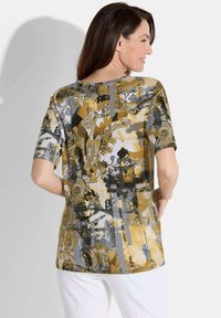 Korte mouwen top in goud, grijs en zwart met een bloemen- en abstracte patroon; soepele stof en ronde halslijn; gemiddelde lengte.