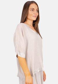 Hellbeige, strukturierte Bluse mit V-Ausschnitt, fallenden Ärmeln und Satinbesatz; lockere Passform erhöht den Komfort und die Bewegungsfreiheit.