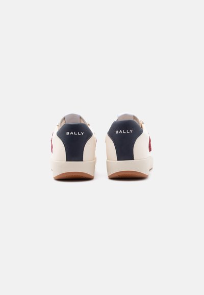 Ζευγάρι λευκών αθλητικών παπουτσιών με μπλε πίσω ελάσματα και λογότυπο "BALLY", εμφανιζόμενα από πίσω σε απλό ανοιχτό γκρι φόντο.