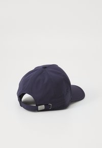 Casquette de baseball bleu marine faite d'un tissu texturé, avec une visière courbée, une sangle ajustable avec un matériel métallique et des œillets de ventilation.