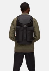 Zaino nero realizzato in materiale resistente, dotato di un cappuccio superiore, tasche frontali, spallacci regolabili e un design a tinta unita.