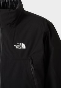 Melnā ūdensizturīgā jaka ar augstu apkakli, kurai ir izteikts balts logotips. Iekļauts sānu rāvējslēdzēja kabata un gluda tekstūra.