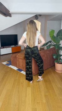 Sorte bukser med paisley-mønster og subtile guldaccenter, parret med en hvid top, sat i et hyggeligt indendørs opholdsområde.