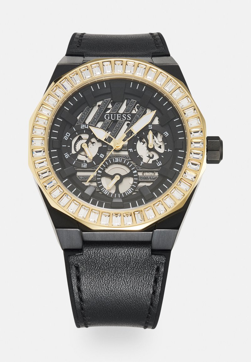 Montre avec bracelet en cuir noir, boîtier octogonal noir, lunette dorée et accents en pierres claires entourant un cadran noir texturé avec des fonctionnalités de chronographe.