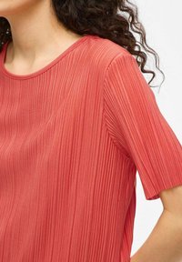 T-shirt rossa a coste in tessuto leggero, con scollatura arrotondata e maniche corte, caratterizzata da una superficie testurizzata e una finitura liscia.