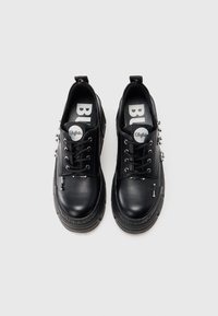 Par de sapatos plataforma de pele de búfalo preta com ferragens prateadas e biqueiras arredondadas sobre fundo branco simples.