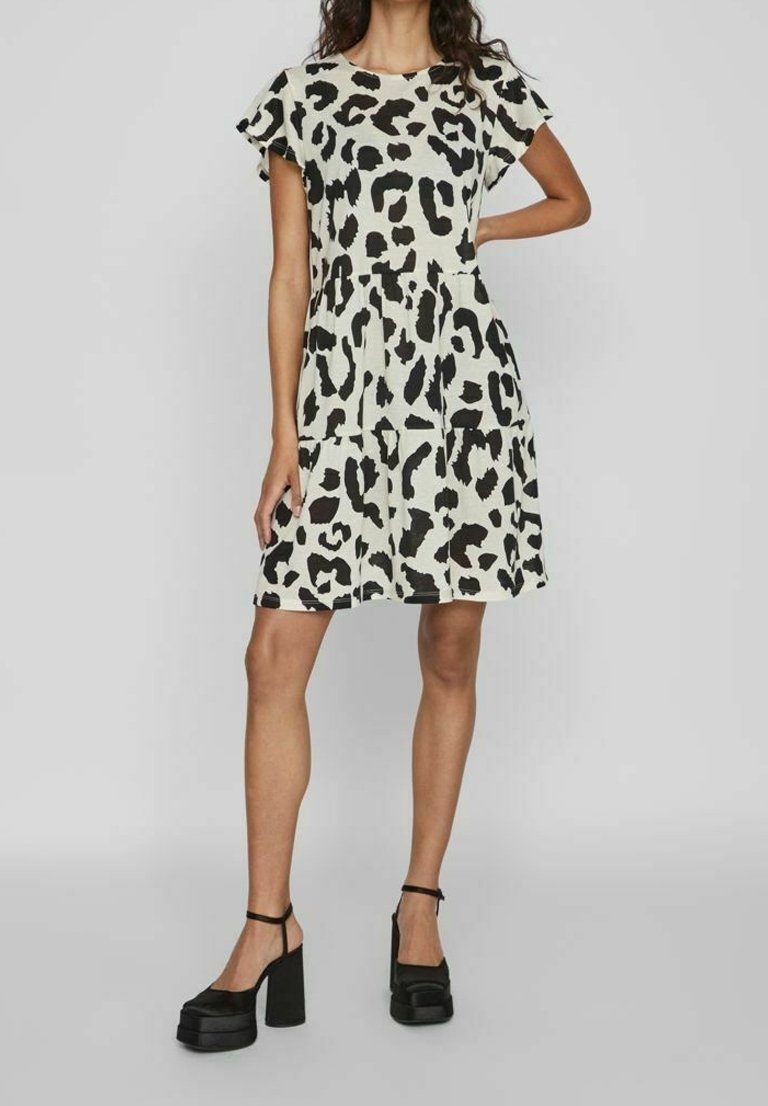 Robe à manches courtes, longueur genou, couleur crème avec un imprimé léopard noir. Tissu léger ; présente un ourlet à volants et une silhouette décontractée.