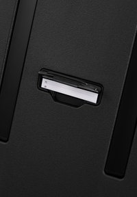Black textured material with a rectangular slot revealing a white insert. Features a small clip above for securing cards or notes.