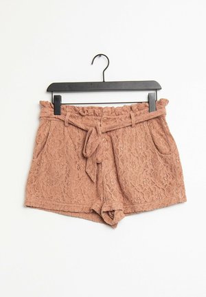 Shorts en dentelle rose poudré, dotés d'une taille froncée, d'une ceinture à nouer et de poches latérales, avec un motif floral texturé sur l'ensemble.