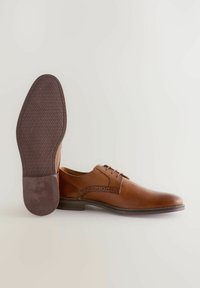 Chaussure habillée en cuir marron avec des accents de design perforé, bout arrondi et semelle en caoutchouc texturé. Fermeture à lacets avec quatre œillets.