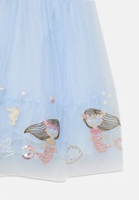 Abito in tulle blu chiaro con disegni di sirena ricamati e paillettes, adornato con conchiglie e cuori lungo l'orlo.