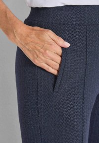 Navy herringbone-gepatroonde broek met een getailleerde pasvorm en zijzak, voorzien van een gestructureerde stof en een gladde tailleband.