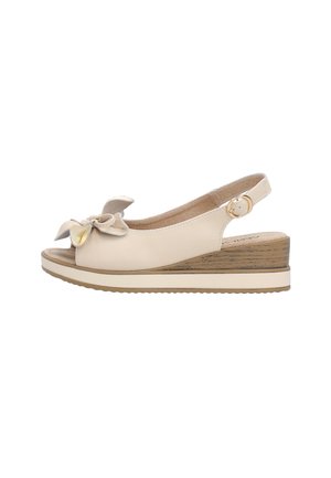 Beżowa damska sandałka na koturnie z odkrytym palcem, ozdobną kokardą, paskiem wokół kostki z pozłacaną sprzączką i platformową podeszwą z fakturą drewna.