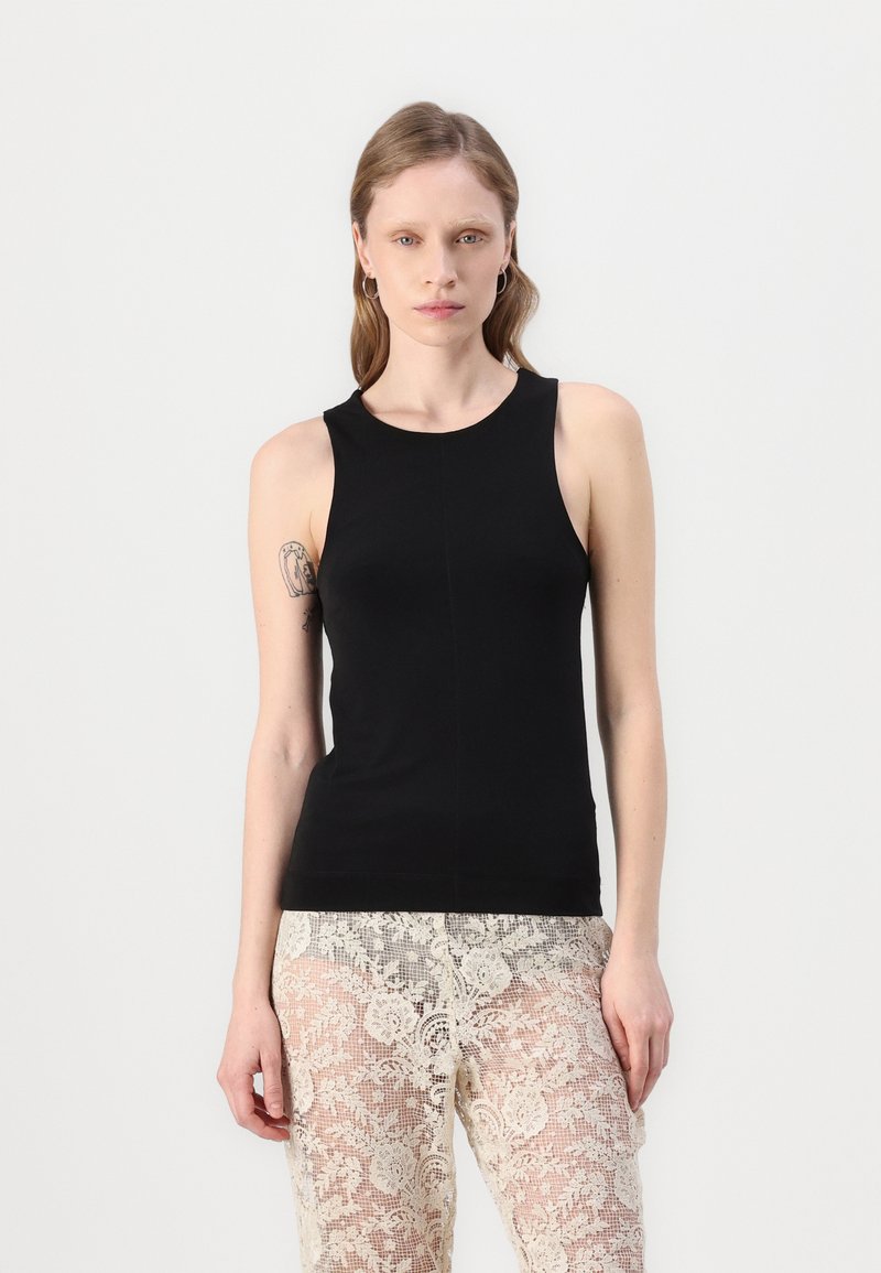 Débardeur noir sans manches en tissu lisse, avec un col rond et une coupe ajustée. Associé à un pantalon en dentelle transparent.