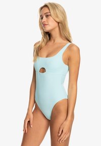 Lichtblauwe éénstuk zwemkleding met een ronde uitsnijding aan de voorkant, brede schouderbanden, een gladde textuur en een aansluitend ontwerp.