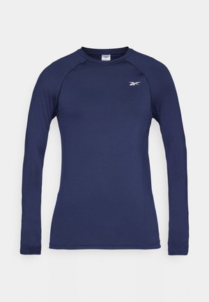 Camisola atlética de mangas longas na cor azul-marinho, feita de tecido liso e respirável. Apresenta um decote redondo e um pequeno logótipo branco no canto superior esquerdo do peito.