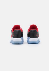 Zapatillas negras y rojas con parte superior de cuero suave y malla, con una entresuela blanca y una suela exterior azul translúcida. Logo de Nike Air exhibido.