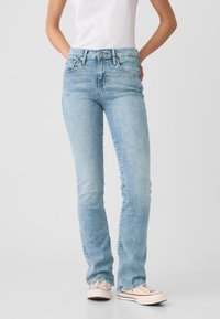 Lichtblauwe denim jeans met een rechte pijp, vijfzakkenontwerp en een klassieke knoopsluiting. Zachte textuur met een vervaagde afwerking.