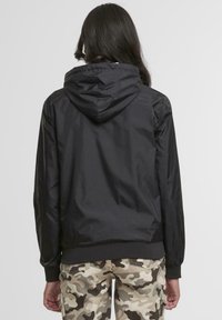 Black hooded jacket with a smooth, lightweight fabric, elastic cuffs, and a hem. The back features a simple design with no visible logos.