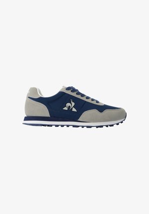 Sneakers da uomo con una tomaia in tessuto blu navy e dettagli in suede grigi, dotati di una suola in gomma bianca, lacci tondi e un logo laterale.