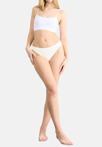 Weißes, leichtes Cropped-Top und creamfarbene Bikini-Unterteile, mit glatter Textur und einfachem Design. Keine Muster oder zusätzlichen Akzente.