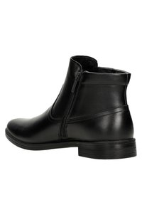 Czarna skórzana botka za kostkę o gładkiej fakturze, z detalem w postaci bocznego zamka, okrągłym noskiem i niskim gumowym obcasem dla stabilności.