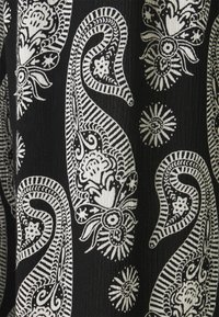 Zwarte stof met witte paisley- en bloemenpatronen, met complexe lijnen, bloemenaccenten en een gestructureerd detail overal.