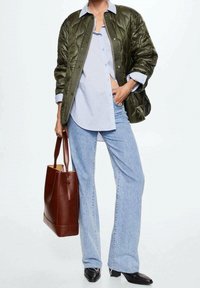 Prošívaná olivově zelená bomber bunda, světle modrá košilová halenka, světle modré zvonové džíny a hnědá kožená kabelka s zipem. Černé boty.