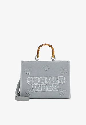 Grå stofhåndtaske med bambushanke, broderede hjerter og frynset tekst "SUMMER VIBES" på forsiden samt en aftagelig skulderrem.