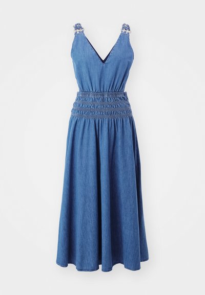 Sininen denimit midi-mekko ilman hihoja, V-pääntie, elastinen rypytetty vyötärö ja röyhelöyksityiskohdat hihnoissa yksinkertaisella taustalla.