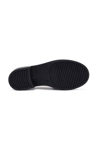 Black rubber shoe sole with a smooth texture, featuring horizontal ridges for traction. The shape is flat and rounded at the toe.