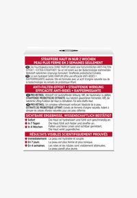 Vit förpackningslåda med röd och svart text, som innehåller flerspråkiga påståenden om en doftfri anti-aging kräm och dess fördelar.