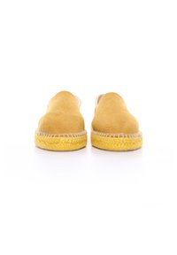 Scarpe slip-on di stoffa gialle con una texture morbida, punta rotonda e dettagli sulla suola intrecciata in stile juta. Fodera interna liscia visibile.