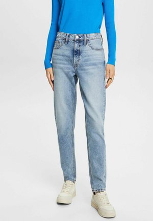Jeans de mezclilla azul claro con un diseño de pierna recta, cintura alta y un estilo clásico de cinco bolsillos, combinados con una blusa azul ajustada y zapatillas blancas.