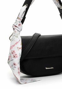 Black leather handbag with a floral-patterned silk scarf tied to the strap. Features a curved shape and a subtle gold brand detail.