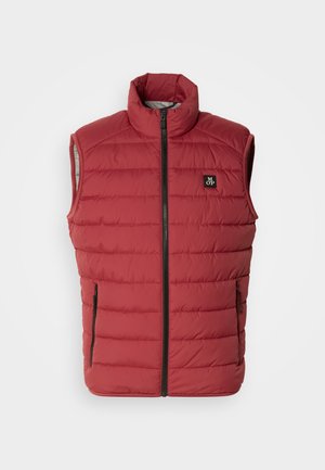 Punane polsterdatud vest kõrge kaelusega, ees tõmblukuga ja kahe küljetaskuga. Omab õmmeldud horisontaalseid paneele ja logotähist.