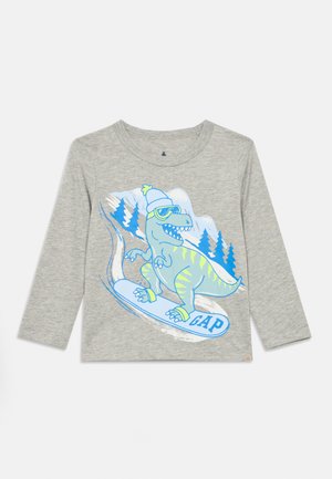 Grå langærmet T-shirt med en farverig tegneseriesneaur, der snowboarder, med et blåt og grønt design og "GAP" på et hvidt snowboard.