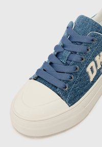 Baskets en denim avec tige en tissu bleu, bout en caoutchouc blanc et lacets assortis bleus. Présente un texte sur le côté dans une couleur claire.