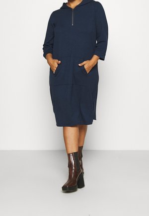 Marineblaues Kapuzenkleid mit einer halben Reißverschlussfront, dreiviertellangen Ärmeln und zwei Seitentaschen. Hergestellt aus weichem, strukturiertem Stoff.