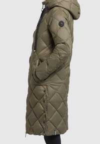 Quilted long parka in olive green with a hood, front pockets, snap buttons, and contrasting black drawstrings. Smooth, shiny finish.