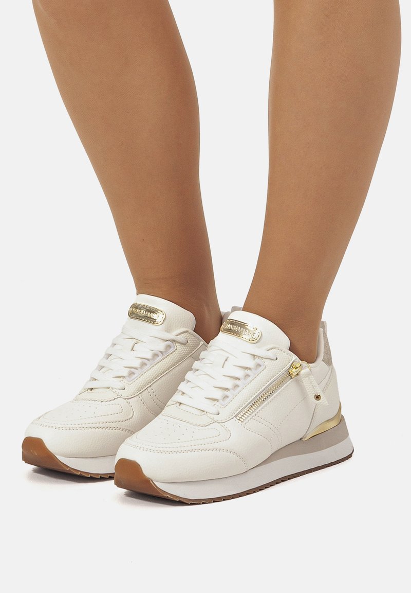 Zapatillas de piel blanca con acentos dorados, textura perforada, un zipper lateral y suela de goma, con puntera redondeada y sistema de cordones.